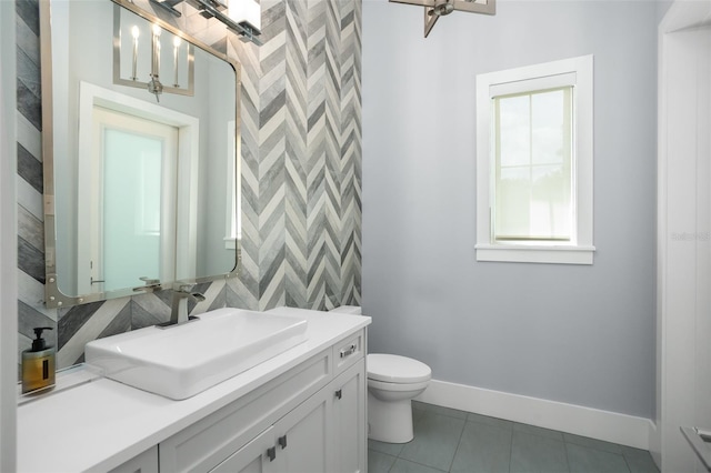 bathroom featuring vanity, toilet, a healthy amount of sunlight, and tile patterned flooring