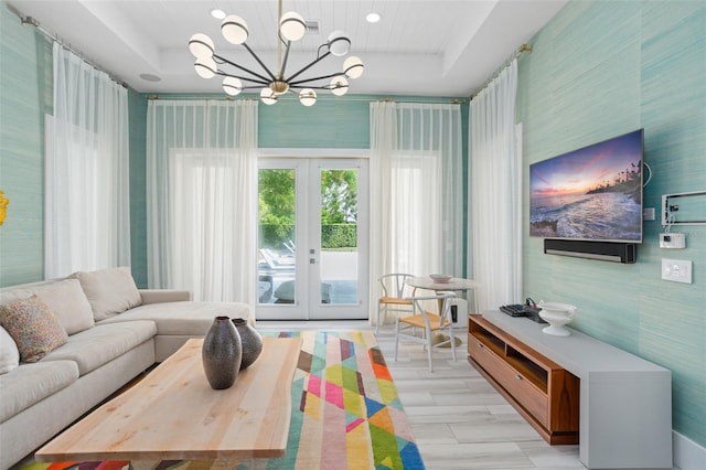 interior space featuring french doors, light hardwood / wood-style floors, an inviting chandelier, and a raised ceiling