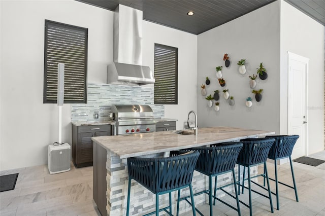 kitchen with wall chimney exhaust hood, sink, a kitchen bar, and kitchen peninsula