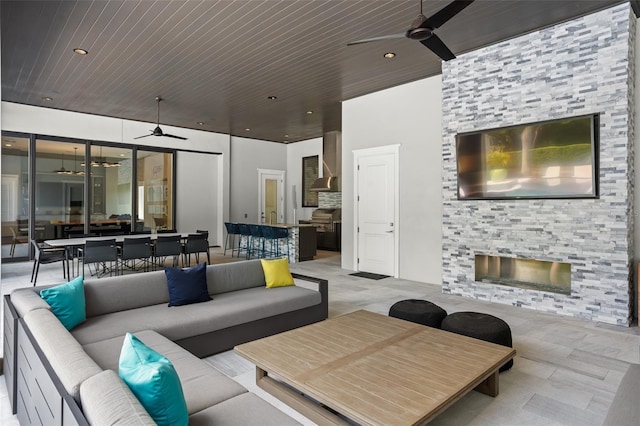 living room featuring ceiling fan, wooden ceiling, and a fireplace