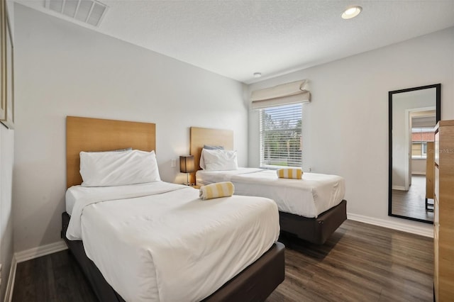 bedroom featuring a textured ceiling and dark hardwood / wood-style floors