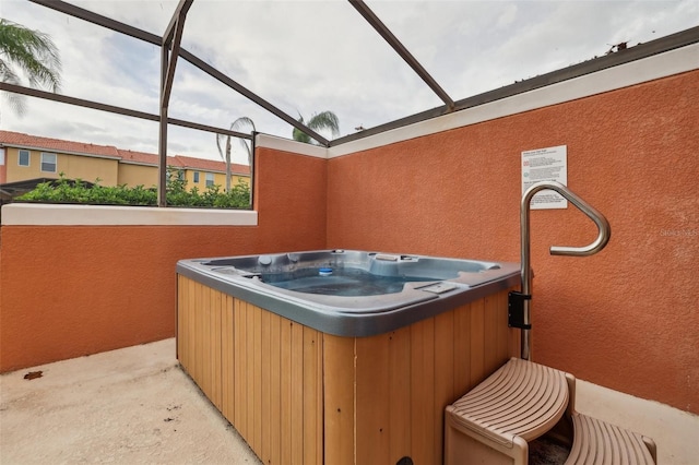 view of patio / terrace with glass enclosure and a hot tub