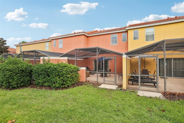 rear view of property featuring a yard, a patio, and glass enclosure