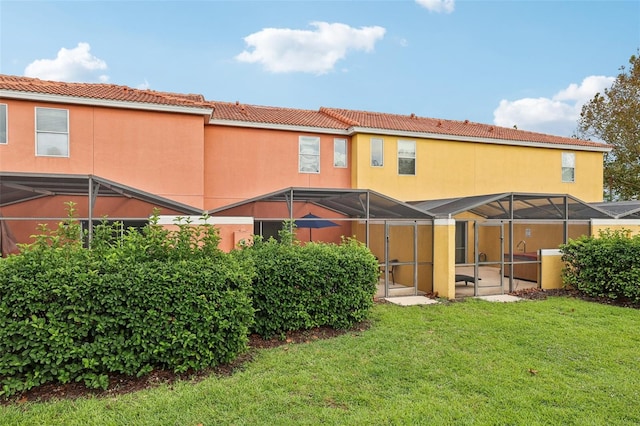 rear view of property featuring a lanai and a lawn