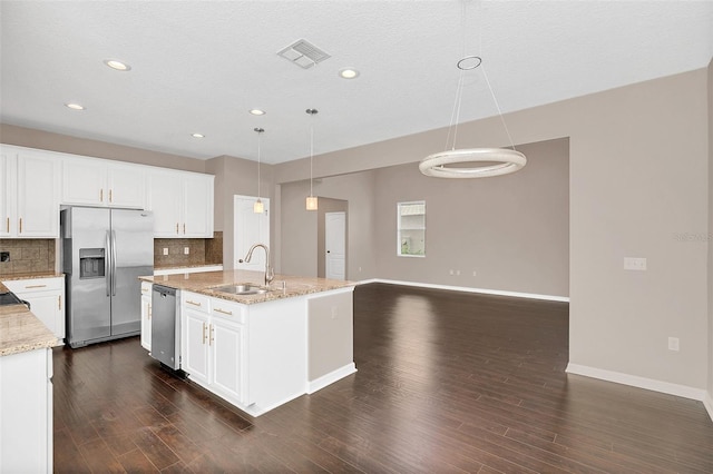 kitchen featuring sink, an island with sink, stainless steel appliances, decorative light fixtures, and dark wood-type flooring