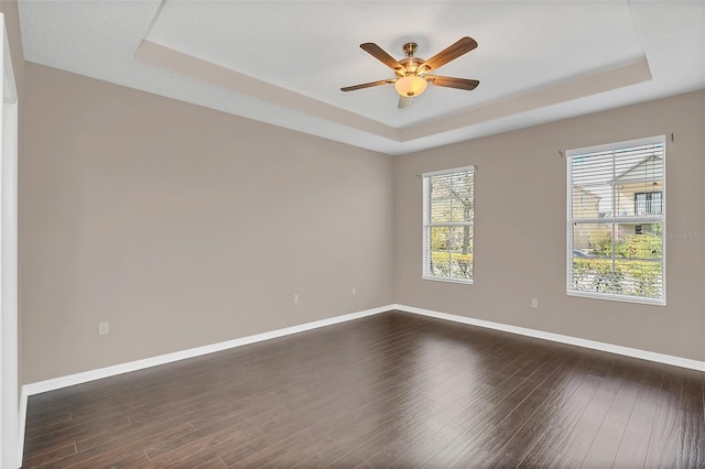 unfurnished room with ceiling fan, dark hardwood / wood-style floors, and a raised ceiling