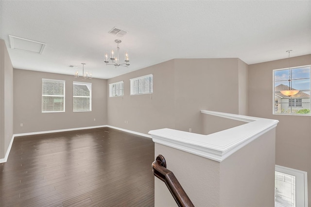 interior space featuring a notable chandelier, a textured ceiling, plenty of natural light, and dark hardwood / wood-style flooring