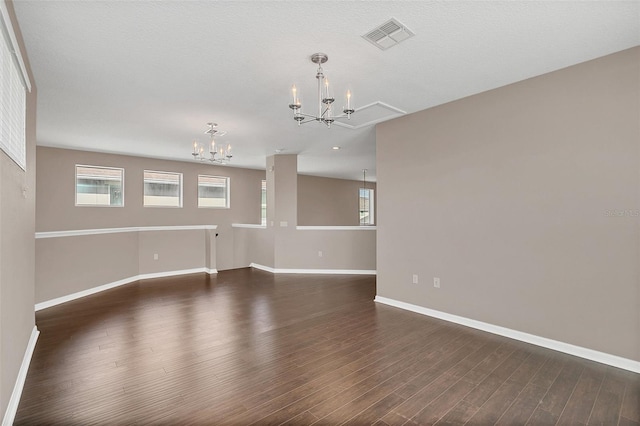 unfurnished room featuring a notable chandelier, a textured ceiling, and dark hardwood / wood-style flooring