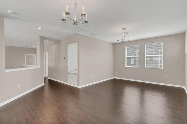 unfurnished room with dark wood-type flooring, a textured ceiling, and an inviting chandelier