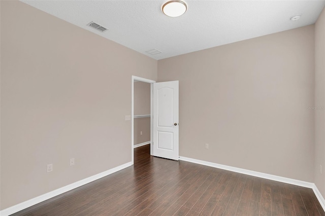 spare room featuring dark wood-type flooring and a textured ceiling