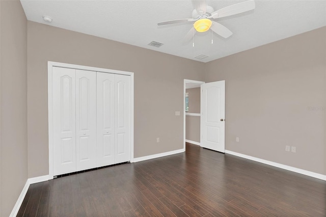 unfurnished bedroom featuring ceiling fan, a textured ceiling, a closet, and dark hardwood / wood-style flooring