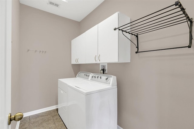 laundry area featuring cabinets, washer and dryer, and light tile patterned flooring