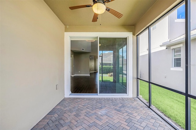 unfurnished sunroom featuring ceiling fan