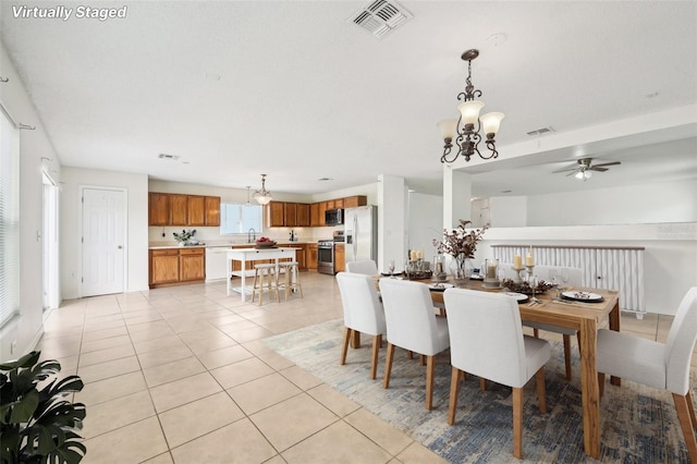 tiled dining space with sink and ceiling fan with notable chandelier