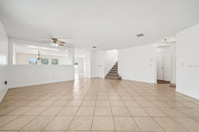 tiled empty room with ceiling fan with notable chandelier