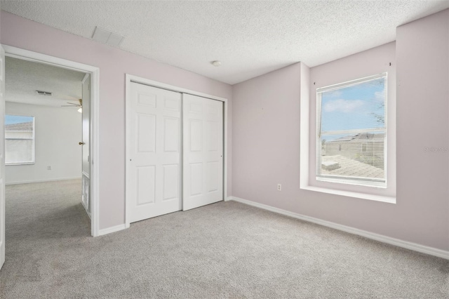 unfurnished bedroom with a closet, light carpet, and a textured ceiling