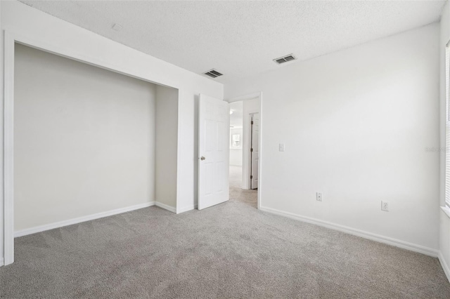 unfurnished bedroom featuring a textured ceiling and light colored carpet