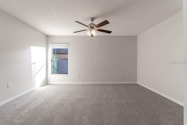 carpeted spare room featuring ceiling fan and a textured ceiling