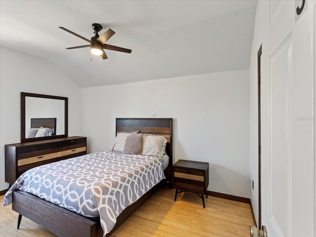 bedroom with ceiling fan, vaulted ceiling, and light wood-type flooring