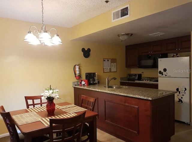 kitchen featuring white refrigerator, a notable chandelier, a textured ceiling, sink, and light stone countertops