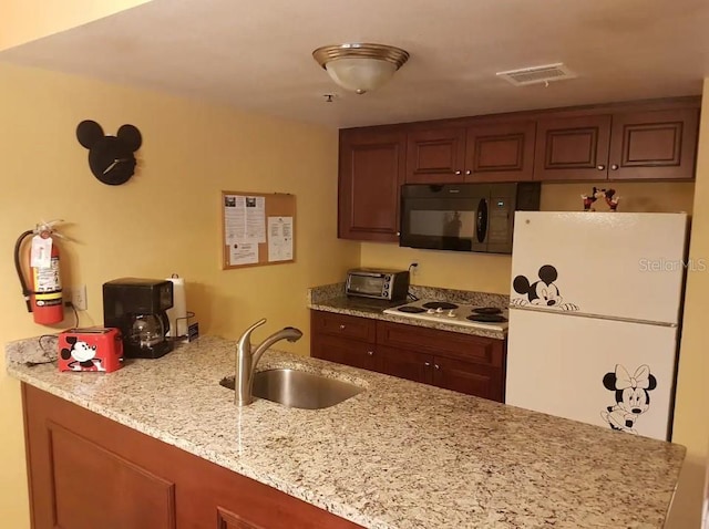 kitchen featuring sink, white appliances, and light stone countertops