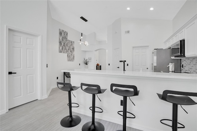 kitchen with white cabinetry, appliances with stainless steel finishes, a breakfast bar area, and kitchen peninsula