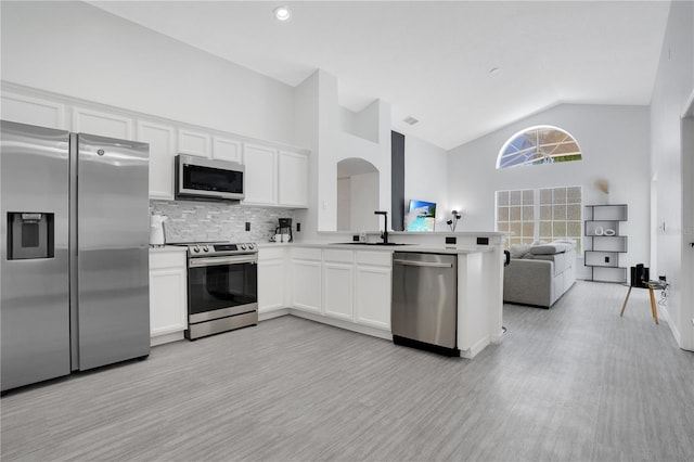 kitchen featuring appliances with stainless steel finishes, white cabinetry, high vaulted ceiling, and sink