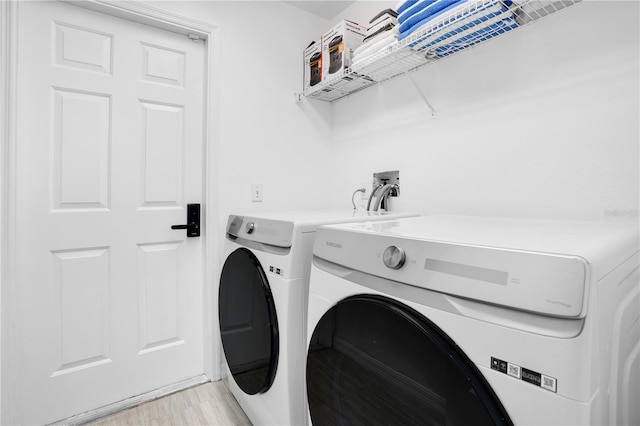 laundry room with independent washer and dryer and light hardwood / wood-style floors