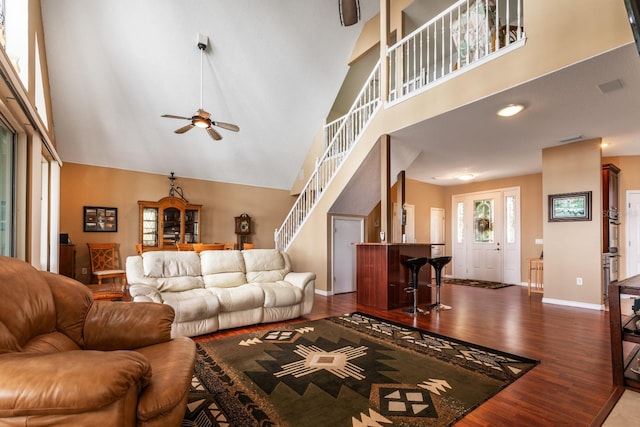 living room with hardwood / wood-style floors, ceiling fan, and a high ceiling