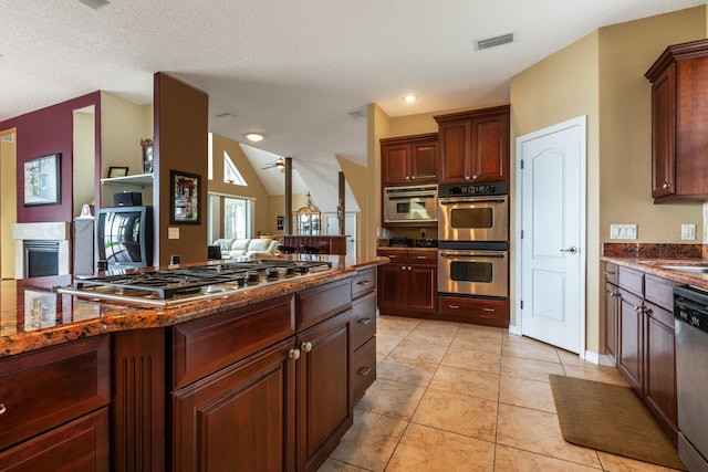 kitchen with appliances with stainless steel finishes, a textured ceiling, vaulted ceiling, ceiling fan, and light tile patterned flooring