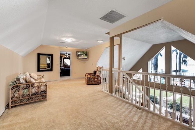 interior space with a textured ceiling, ceiling fan, carpet, and vaulted ceiling