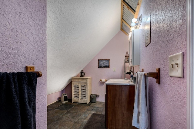 bathroom with vanity, a textured ceiling, and vaulted ceiling