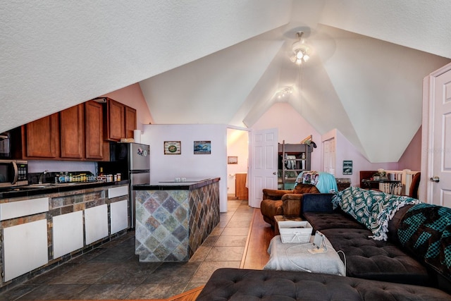 living room featuring a textured ceiling, dark tile patterned flooring, and lofted ceiling