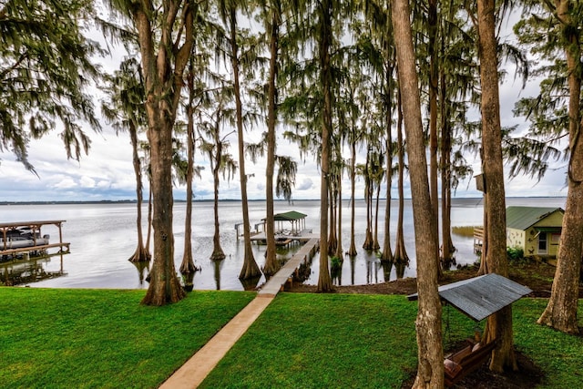 view of dock with a lawn and a water view