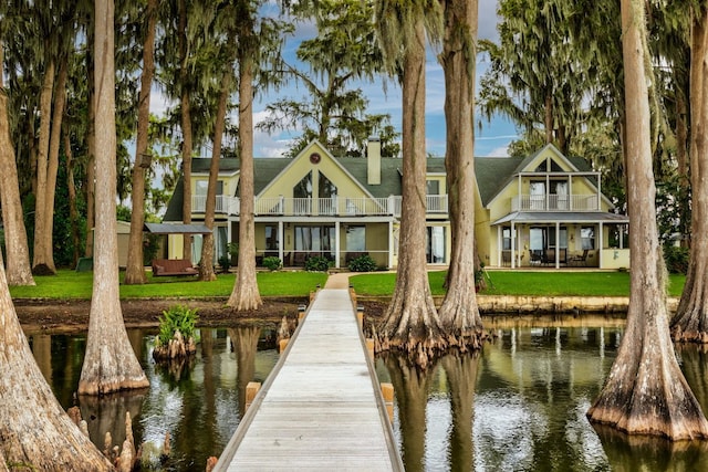 dock area featuring a balcony, a lawn, and a water view