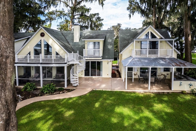 rear view of house with a balcony, a yard, and a patio