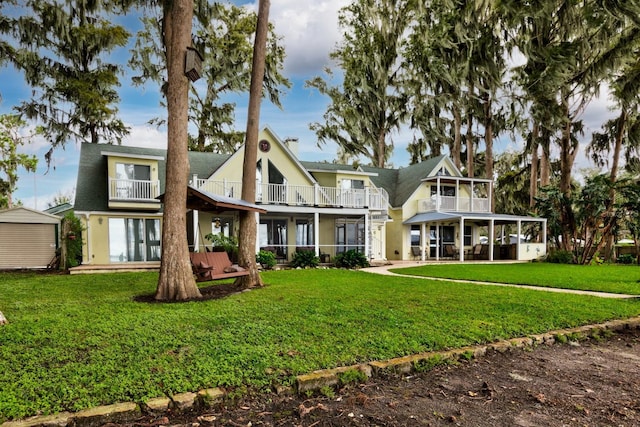 back of house with a lawn and a balcony