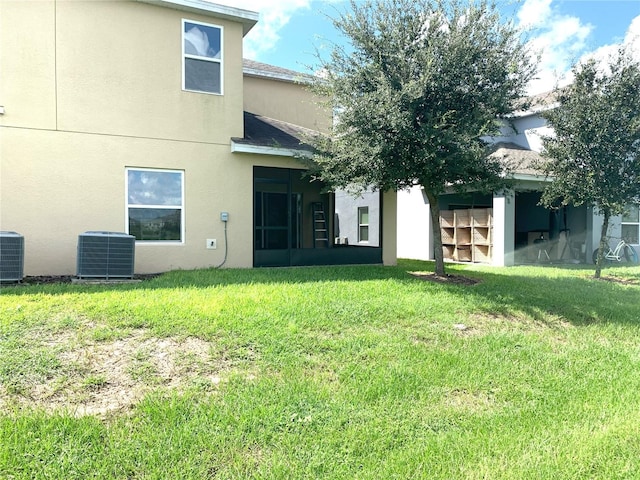 rear view of property with cooling unit and a lawn