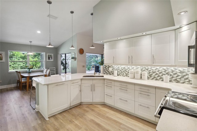 kitchen with white cabinetry, sink, kitchen peninsula, and hanging light fixtures