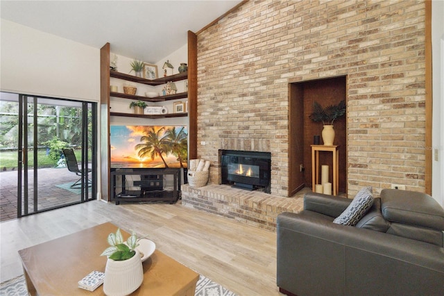 living room with high vaulted ceiling, hardwood / wood-style flooring, and a brick fireplace