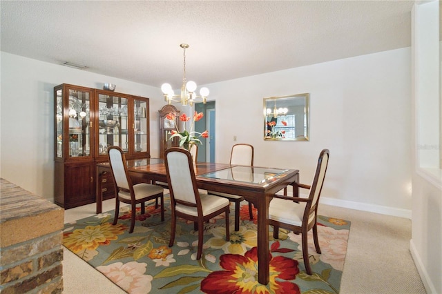 dining space featuring light carpet, a notable chandelier, and a textured ceiling