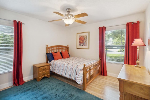 bedroom with multiple windows, hardwood / wood-style flooring, and ceiling fan