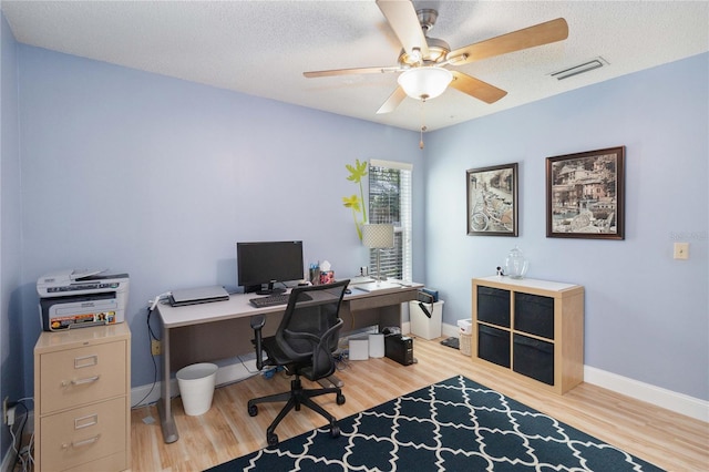 home office featuring ceiling fan, wood-type flooring, and a textured ceiling