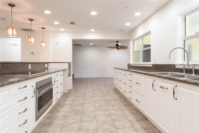 kitchen featuring white cabinets, hanging light fixtures, stainless steel oven, black electric stovetop, and sink