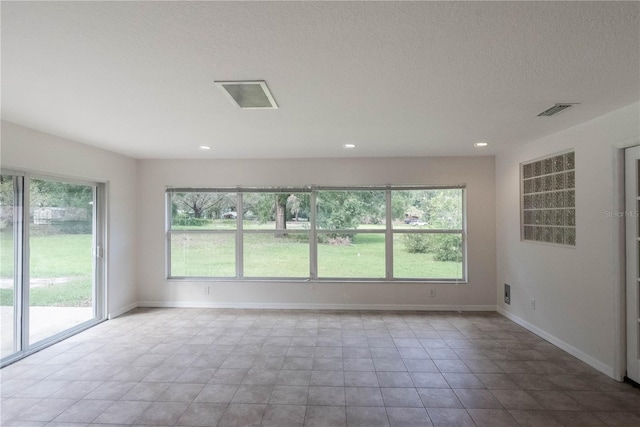 tiled empty room with a textured ceiling