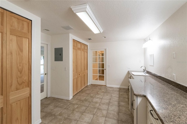 kitchen with light tile patterned flooring, a textured ceiling, electric panel, and sink