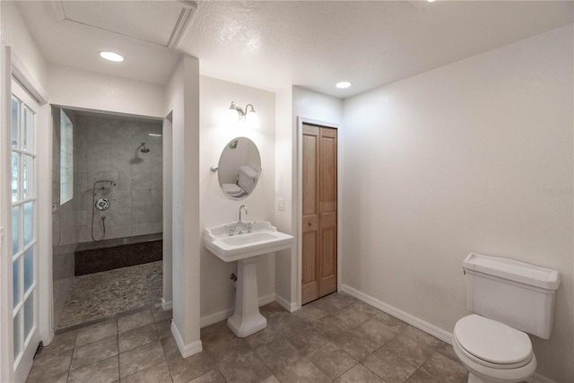 bathroom with toilet, tile patterned flooring, and tiled shower