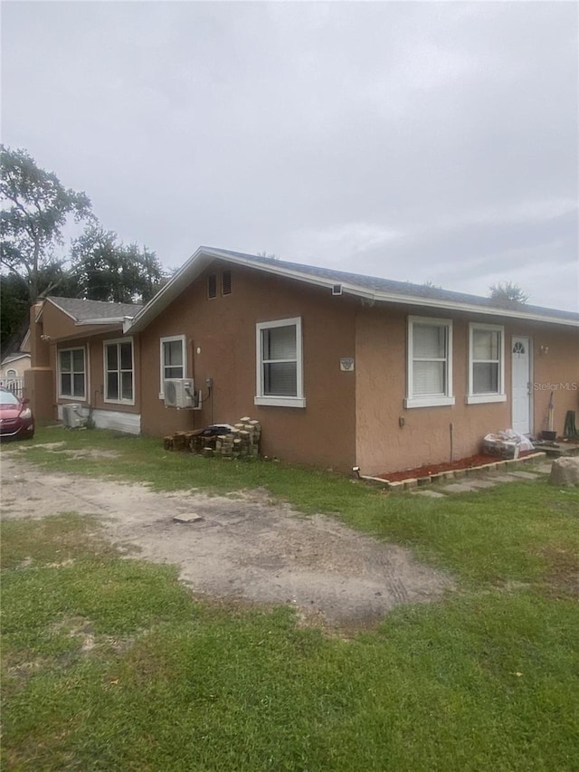 1801 Daniels St, Kissimmee, FL 34746 - view of home's exterior with stucco siding, a lawn, driveway, and cooling unit