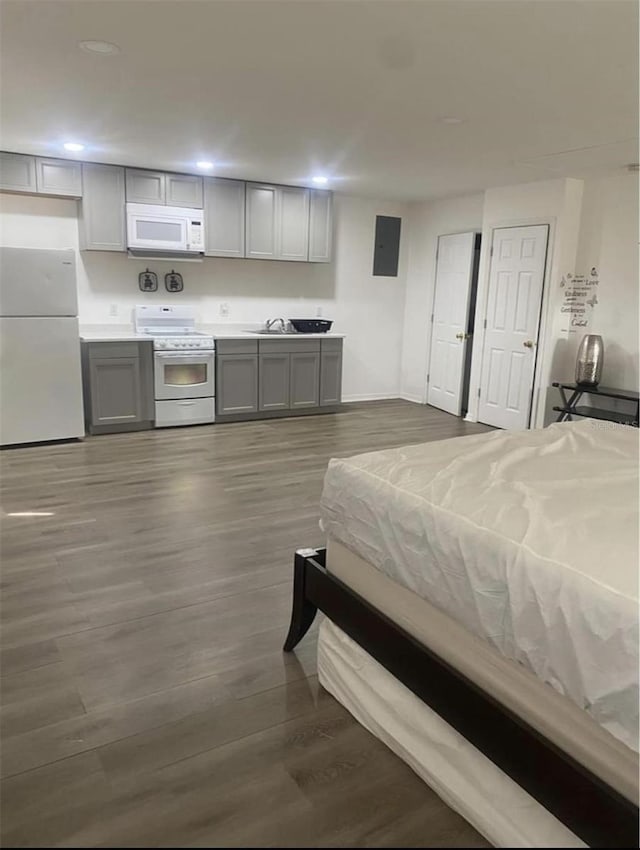 bedroom with dark hardwood / wood-style flooring, sink, and white refrigerator