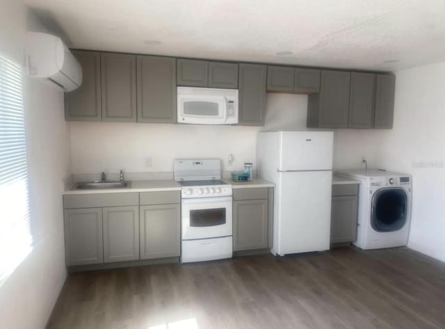 kitchen featuring washer / clothes dryer, an AC wall unit, sink, white appliances, and dark hardwood / wood-style flooring